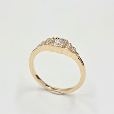 Bague en or jaune avec diamant central serti clos et pavage de diamants sur gradins